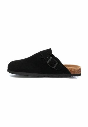 Zueco de ante negro con punta redondeada y hebilla lateral. Plantilla de corcho y suela de goma, con una textura suave y mate.