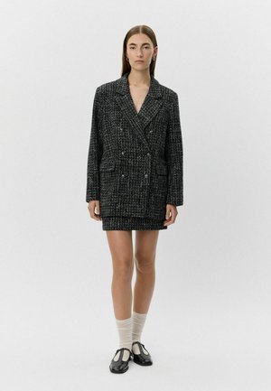 Zwart-wit geblokt blazer jurk met dubbele knopen, notch-lapel, twee voorkruiszakken en textiele stof.