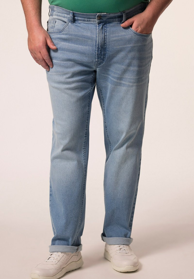Jeans in denim azzurro chiaro con vestibilità comoda, caratterizzati da un design a cinque tasche, chiusura con bottone frontale e orli arrotolati. Indossati con sneakers bianche.