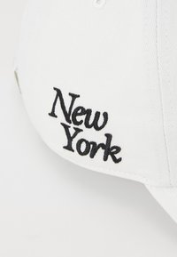 Cappellino da baseball bianco con il testo ricamato "New York" in nero. Il materiale sembra cotone con una superficie liscia e visiera curvata.