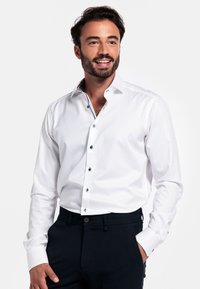 Witte overhem shirt met een contrasterende gepatineerde binnenkraag, knoopsluiting en Marineblauwe knopen. Glad materiaal met een gestructureerde pasvorm.