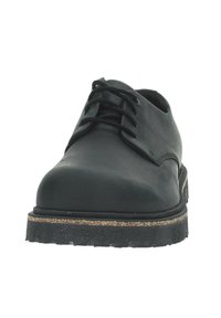 Scarpa in pelle nera con lacci, punta arrotondata, superficie texturizzata e suola in gomma spessa con uno strato di sughero e un motivo battistrada.