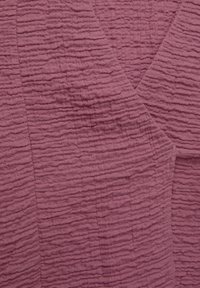 Texturerad tyg i dämpad mauve med horisontella rynkmönster. Mjukt, lätt material med en subtil lyster och lagerutseende.