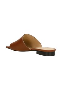 Sandale en cuir marron à glissière avec un design à bout ouvert, petit talon noir et texture lisse. Style minimaliste avec une silhouette incurvée.