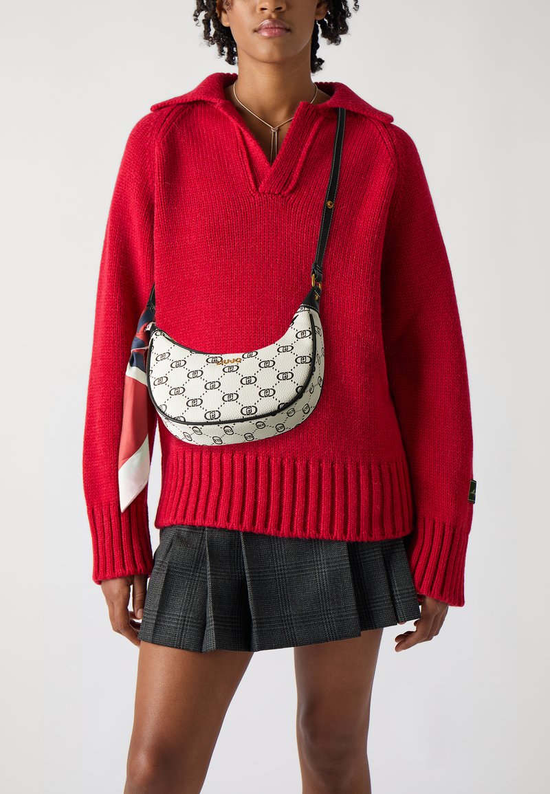 Strikket rød sweater med bred krave, kombineret med en plisseret sort nederdel. En lille cremefarvet taske med et logo mønster og stofscarf som accent.