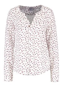 Vit skjorta med knappar som har ett upprepande mönster av fjärilar i rosa och lila, med långa ärmar och en mjuk, slät textur.