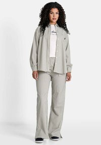 Gestreiftes Button-Up-Hemd und passende Hose in Hellgrün und Weiß. Weicher Stoff mit lockerer Passform, ausgestattet mit einem elastischen Bund und geknöpften Ärmeln.
