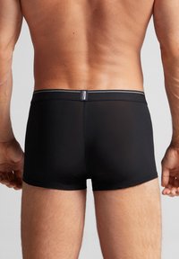 Svarta boxertrosor i mjukt material, med en åtsittande passform, minimalistisk design och en elastisk midjeband med en liten etikett.