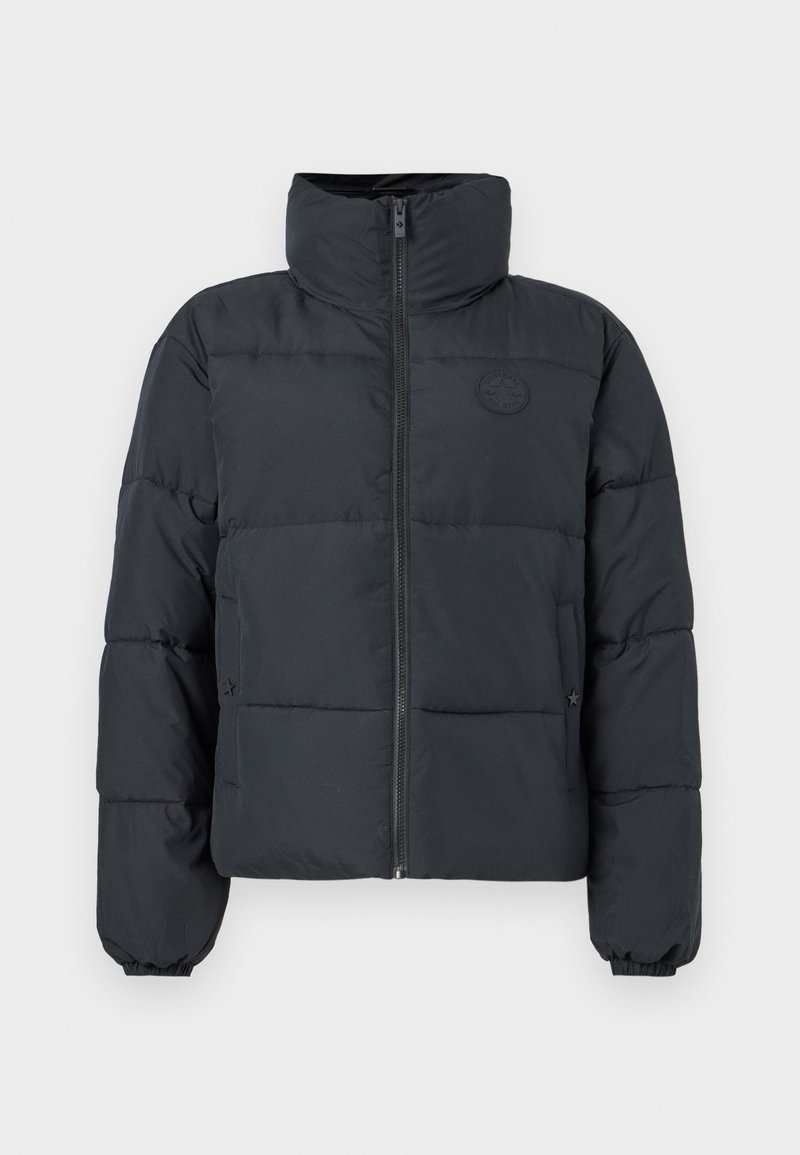 Polstret jakke med lynlås i sort med høj krave, med vandrette quiltede sektioner og et rundt logo-patch på brystet.