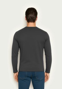 Langärmliges, dunkelgraues Hemd aus weichem Stoff, mit Rundhalsausschnitt und tailliertem Design. Die Rückansicht zeigt die glatte Textur und den schlichten Stil.