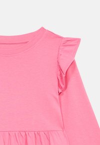 Ροζ μακρυμάνικο πουκάμισο με στρογγυλή λαιμόκοψη και φουσκωτά μανίκια, φτιαγμένο από μαλακό βαμβάκι με λεία υφή και φαρδύ στρ�ίφωμα.