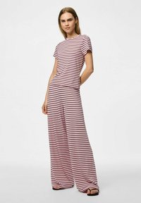 Gestreepte tweedelige outfit met een roze top met korte mouwen en wijde broek, beide van een zachte stof met horizontale zwarte strepen.