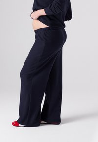 Navyblaue, locker sitzende Hose aus weichem Stoff mit elastischem Bund. Kombiniert mit roten und weißen Socken.