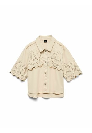 Chemise beige à manches courtes avec boutonnière, brodée de motifs en dentelle ajourée sur les manches et la partie supérieure de la poitrine, avec un design aux bords festonnés.