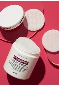 Bocal blanc avec du texte noir, contenant des tampons de resurfacement au rétinol glycolique. Tampons lisses et texturés sur un fond rose, bocal partiellement ouvert.