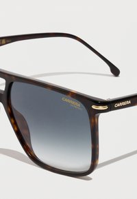 Gafas de sol de carey marrón con lentes graduales grises, que presentan acentos de metal dorado y la marca "CARRERA UV PROTECT" en la lente.