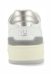 Weißes Ledersneaker mit einem kragenförmigen Detail in metallischem Silber. Verfügt über eine dicke weiße Sohle mit grauen Akzenten und einem geprägten "HUB"-Logo.