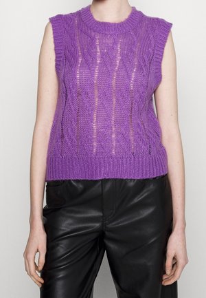 Pull sans manches violet à torsades avec un col rond, porté avec un pantalon en cuir noir.