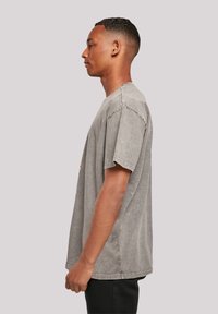 Gray cotton t-shirt with short sleeves, relaxed fit, crew neck, and distressed texture; features a subtle front logo design.
