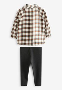 Kreminės, oranžinės ir juodos spalvų langelinės marškinėliai su ilgomis rankovėmis ir mygtukais ant rankovių, derinami su juodomis juostuotomis legingais. Abi dalys pagamintos iš minkštos medžiagos.