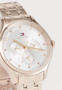 Reloj de metal en oro rosa con una esfera texturizada plateada, tres subesferas y marcadores de hora elevados. Presenta una pulsera de eslabones pulidos y una corona.