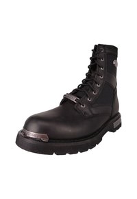 Botín de cuero negro con diseño de cordones, suela de goma y detalles en metal plateado. Cuenta con puntera reforzada y paneles de nailon.