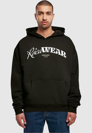 Sort hættebluse med frontlomme og snoretræk i hætten. Har hvidt Roca Wear-logo og teksten "Etableret 1999". Glat stofstruktur.