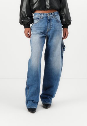 Bredde ben blå denimjeans med en falmet vask, doble sidelommer og rette hemmer. Kombinert med en svart kort lærjakke.