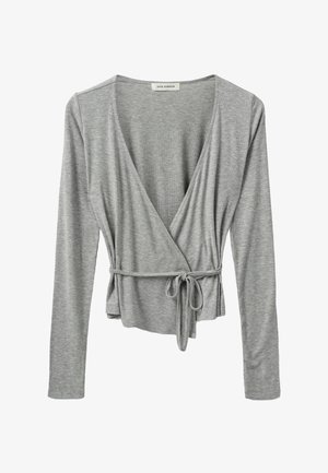 Grijze lange mouw wikkeltop in een zachte ribbeltextuur met een V-hals en een verstelbare strik in de taille, met een subtiele, ontspannen uitstraling.