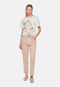 Light pink denim trousers with a relaxed fit, paired with a white graphic t-shirt featuring black floral illustrations and pink lettering.