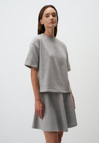 Grijze katoenen blend top en uitlopende rok. Korte mouwen, ronde hals en een gladde textuur. Eenvoudig, casual ontwerp zonder patronen of versieringen.