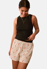 Black sleeveless top and light-colored shorts with a striped pattern and red chili pepper prints, featuring an elastic waistband.