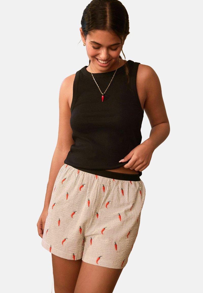 Black sleeveless top and light-colored shorts with a striped pattern and red chili pepper prints, featuring an elastic waistband.