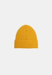 Bonnet en tricot jaune avec revers sur fond blanc uni.