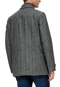 Grau kariertes Blazer im Fischgrätmuster mit Reverskragen, strukturiertem Stoff und taillierter Passform. Rückansicht mit langen Ärmeln und einfarbigen Akzenten.