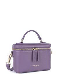 Paarse leren handtas met een gestructureerd ontwerp, gouden hardware, bovenhandgreep en afneembare schouderband; voorzien van een ritssluiting en decoratieve franjes.