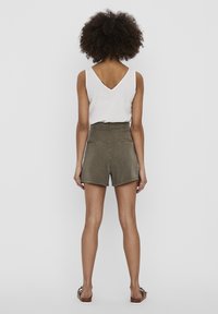 Olive green high-waisted shorts with a back zipper, two back pockets, and a smooth texture, paired with a white V-neck tank top.