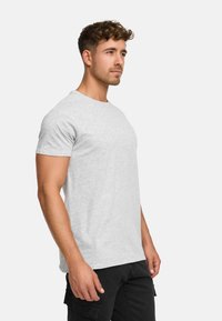 Hellgrau kurzes T-Shirt aus weichem Material mit klassischem Rundhalsausschnitt und lockerer Passform, kombiniert mit schwarzen Cargo-Hosen.