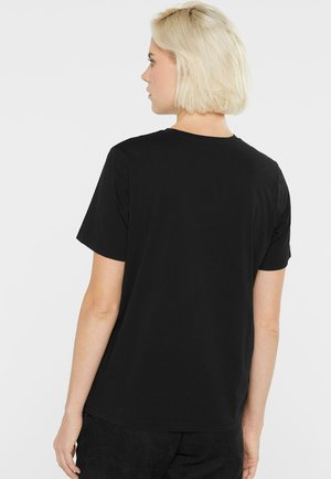 Schwarzes Baumwoll-T-Shirt mit kurzen Ärmeln und Rundhalsausschnitt, entworfen mit einer lässigen Passform und glatter Textur.