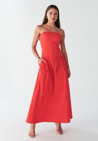 Rihmadeta punane maxi kleit, millel on liibuv ülakehaosa, voolav seelik ja küljetaskud. Sile kangastekstuur, põrandapikkuses disain.