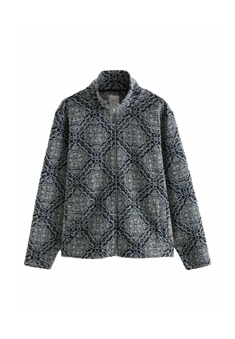 Quiltet zip-jakke med høj krave, prydet med et navy og creme blomster mønster, struktureret stof og talje lommer på hver side.
