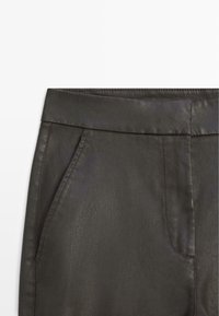 Close-up of dark gray pants waistband and side pocket with visible stitching on a white background.