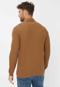 Bruine lange mouwen shirt van gestructureerde stof, met een kraag, een iets losse pasvorm en een afgeronde zoom, gecombineerd met blauwe jeans.