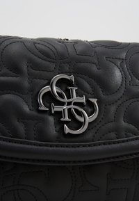 Black leather handbag with quilted texture featuring a prominent metallic logo accent. Compact design with a structured shape and smooth finish.