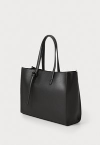 Zwarte leren tote bag met een rechthoekige vorm, twee lange handvatten en een gladde textuur. Kenmerkt zich door een geknoopte detail op één handvat.