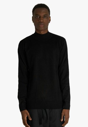 Maglione nero a collo alto con maniche lunghe, realizzato in tessuto a maglia liscia. Presenta una silhouette aderente con polsini e orlo a coste.