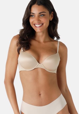 Reggiseno imbottito beige con ferretto, texture liscia, spalline regolabili e forma del coppa arrotondata. Abbinato a mutandine senza cuciture coordinate.