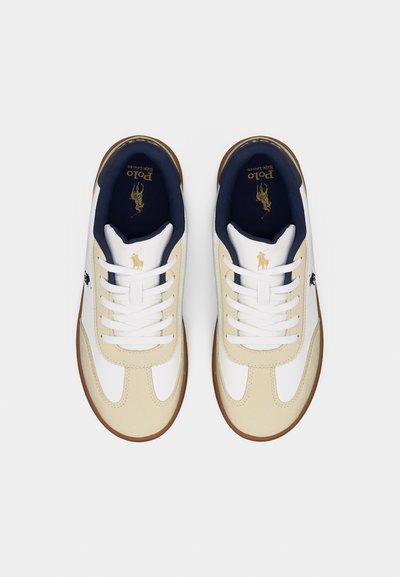 Ζευγάρι λευκών και μπεζ αθλητικών παπουτσιών Polo Ralph Lauren με ναυτικό μπλε επένδυση και χρυσό λογότυπο, εμφανιζόμενο από πάνω σε λευκό φόντο.