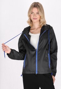 Giacca leggera nera con cappuccio, dotata di zip e cordini blu. Polsini e orlo elastici, texture liscia, adatta per un look casual.