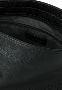Borsa in pelle nera con un'esterno testurizzato, dotata di un interno foderato e chiusura con zip. Sono visibili più scomparti per un'organizzazione ottimale.